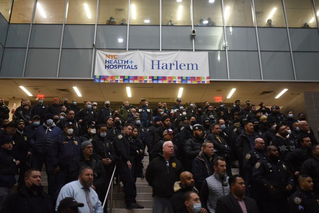 Scores of police officers gather at Harlem Hospital after a police officer is killed and another is in critical condition